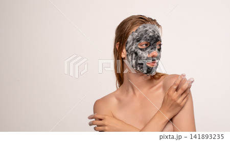 Woman enjoying a beauty routine, applying a charcoal oxygen bubble mask for deep skin cleansing and refreshing Woman enjoying a beauty routine, applying a charcoal oxygen bubble mask for deep skin cleansing and refreshing 141893235