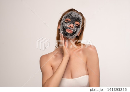 Woman applying purifying charcoal bubble mask for skincare treatment, enjoying beauty and wellness routine at home Woman applying purifying charcoal bubble mask for skincare treatment, enjoying beauty and wellness routine at home 141893236