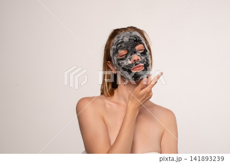 Woman applying purifying charcoal bubble mask for glowing skin, engaging in self-care spa treatment Woman applying purifying charcoal bubble mask for glowing skin, engaging in self-care spa treatment 141893239