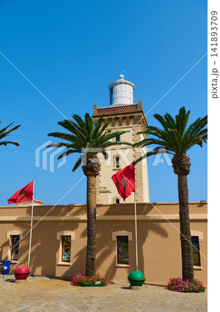 Tangier lighthouse with palm trees and Moroccan flags under clear blue sky Tangier lighthouse with palm trees and Moroccan flags under clear blue sky 141893709