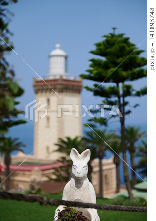 Rabbit statue in coastal garden with lighthouse backdrop in Tangier Morocco 141893748