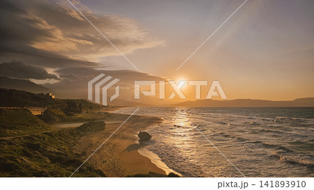 Scenic golden sunset view over sandy Mediterranean sea beach with calm waves and distant coastal mountains under cloudy sky on Crete island in Chania Greece 141893910