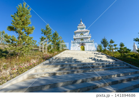 White Buddhist Pagoda Temple with Stone Stairs and Blue Sky White Buddhist Pagoda Temple with Stone Stairs and Blue Sky 141894686