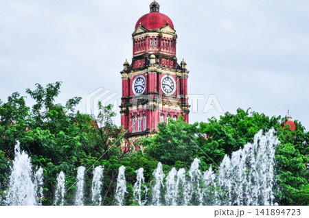 Historic Red Clock Tower with Fountains and Green Trees 141894723