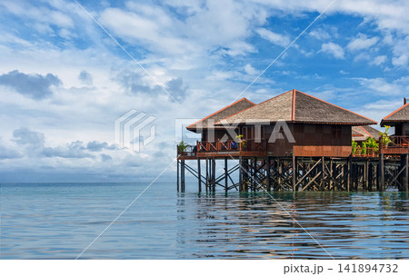 Overwater Bungalows on Tropical Sea Under Blue Cloudy Sky Overwater Bungalows on Tropical Sea Under Blue Cloudy Sky 141894732