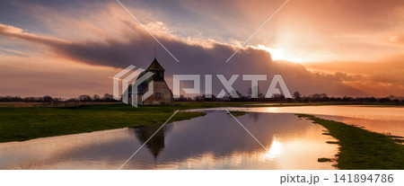 Historic Church by River at Dramatic Sunset in Rural Landscape Historic Church by River at Dramatic Sunset in Rural Landscape 141894786