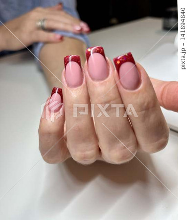 Woman's hand with red french manicure, nail design, christmas Woman's hand with red french manicure, nail design, christmas 141894840