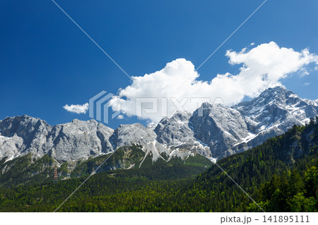 Travel landscape of Zugspitze Alps in Bavaria, Germany, scenic summer nature panorama with forest, snow mountains peak. Alpine landscape Travel landscape of Zugspitze Alps in Bavaria, Germany, scenic summer nature panorama with forest, snow mountains peak. Alpine landscape 141895111