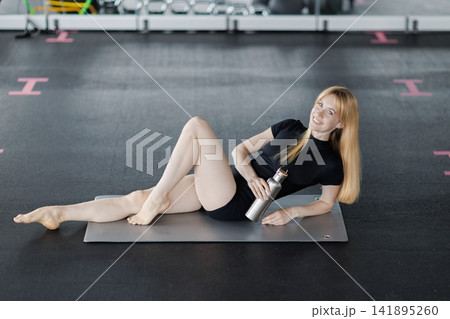 Woman relaxing on yoga mat after workout 141895260