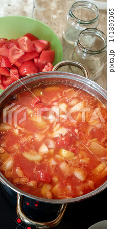 Canning tomatoes in a pot for making lecho in a kitchen 141895365