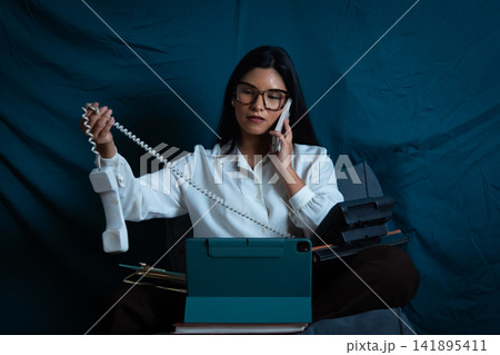 Businesswoman multitasking with multiple phones and technology 141895411