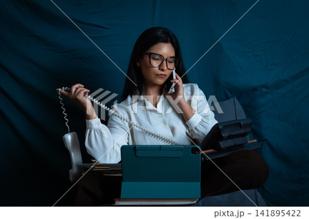 Businesswoman multitasking with multiple phones and technology Businesswoman multitasking with multiple phones and technology 141895422