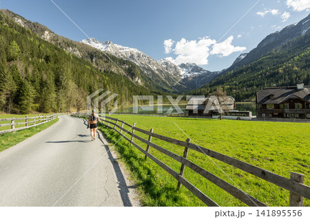 Woman walking on road near Jagersee lake in Austrian Alps 141895556