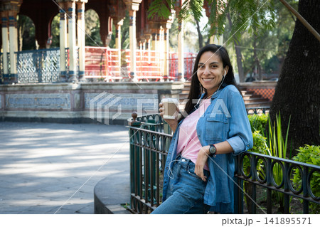 Smiling woman enjoying coffee in morisco kiosk park Smiling woman enjoying coffee in morisco kiosk park 141895571