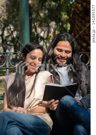 Happy couple reading book together in park 141895577
