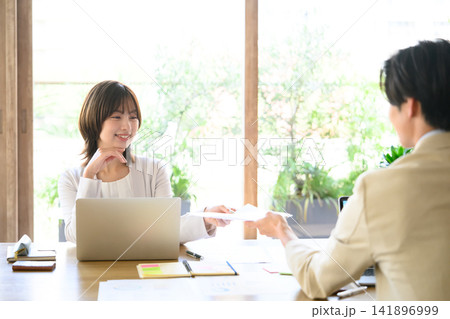 資料を受け取る女性、PCで仕事をする 141896999