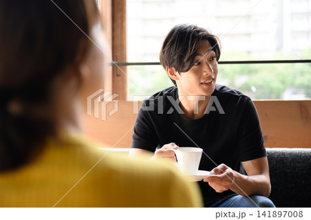 コーヒーカップを持つ男性、女性と会話中 141897008