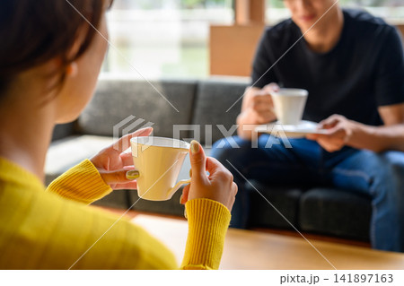 コーヒーカップを持つ男女、カフェで会話 コーヒーカップを持つ男女、カフェで会話 141897163