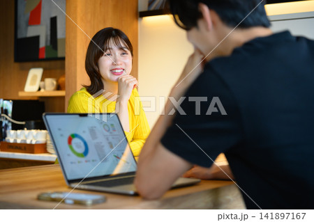 ノートパソコンと笑顔の女性、カフェで会話 ノートパソコンと笑顔の女性、カフェで会話 141897167