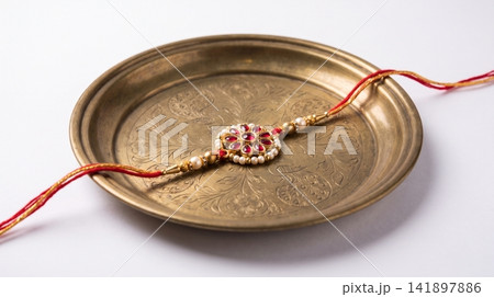 Festive rakhi thread bracelet placed on an antique brass plate with bracelet festival ornament tradition celebration handmade ceremonial decorative heritage auspicious wearable accessory 141897886
