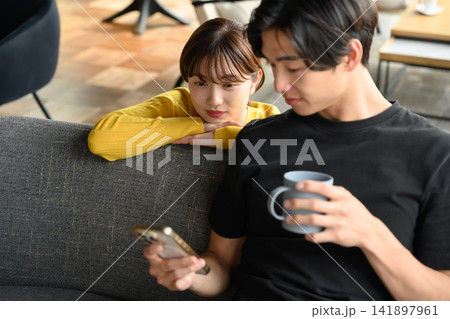 ソファでスマホを見る男性と女性 ソファでスマホを見る男性と女性 141897961