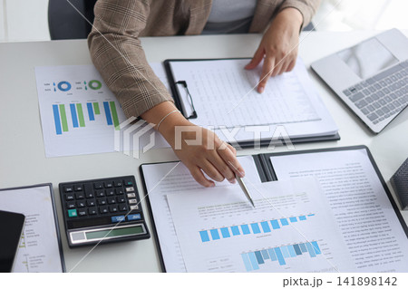 Professional Businesswoman Reviewing Financial Reports and Data Analysis in Modern Office. Professional Businesswoman Reviewing Financial Reports and Data Analysis in Modern Office. 141898142