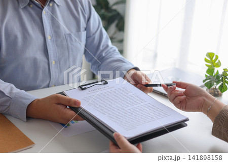 Businessman Handing Over Contract and Pen for Signature in Workplace. Businessman Handing Over Contract and Pen for Signature in Workplace. 141898158