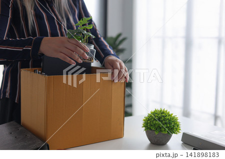 Close-up of Employee Packing Stuff from Working Desk After Quitting Job. Close-up of Employee Packing Stuff from Working Desk After Quitting Job. 141898183