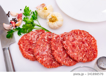 Raw handmade minced pork burgers patties on board Raw handmade minced pork burgers patties on board 141898570