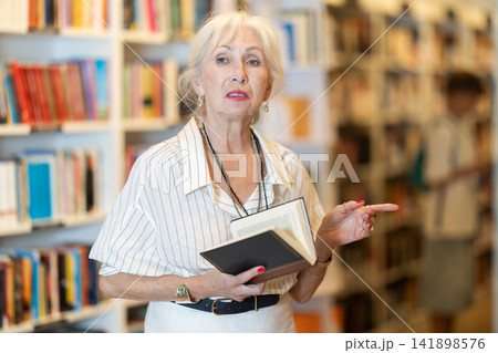 Senior woman choosing books in large bookstore Senior woman choosing books in large bookstore 141898576
