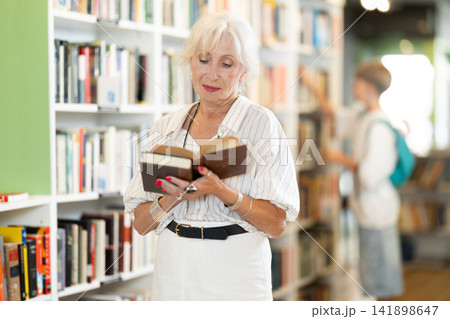 In bookstore senior woman choose book In bookstore senior woman choose book 141898647