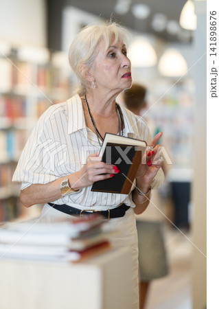 Elderly woman choosing book in bookstore Elderly woman choosing book in bookstore 141898676