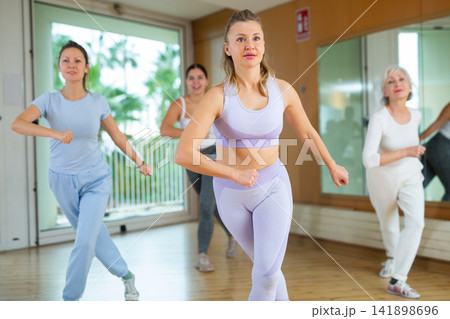 Excited positive women of different ages performing modern dancing exercises in school for adults 141898696