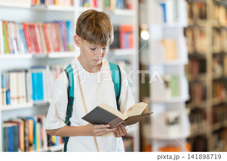 In bookstore teen boy choose book 141898719