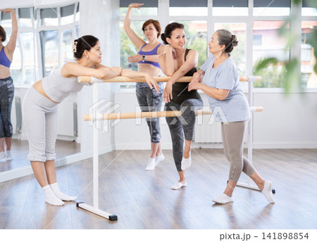 Group of women relaxing at barre after amateur ballet rehearsal 141898854