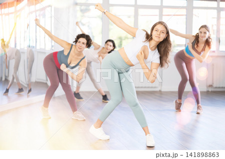 Expressive young woman learning street dancing during group class Expressive young woman learning street dancing during group class 141898863