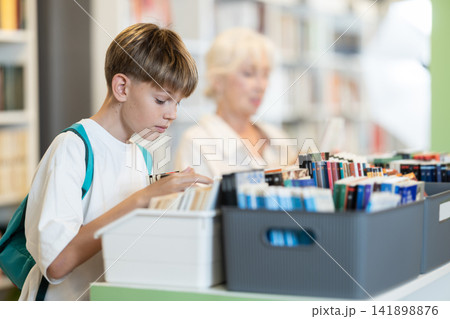 Teenage boy choosing book in bookstore 141898876