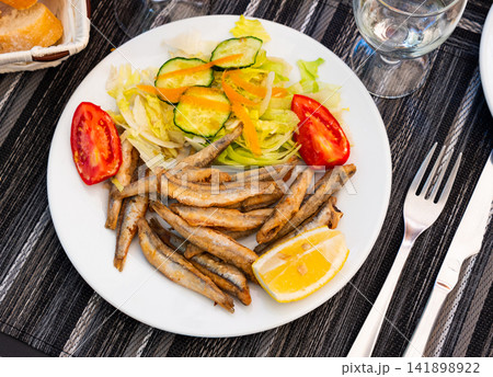 Deep fried anchovies with vegetable garnish and fresh lemon Deep fried anchovies with vegetable garnish and fresh lemon 141898922