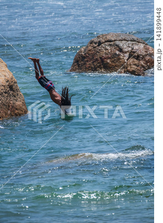 Young cliff jumper diving from rocks into the ocean at Galle Fort, Sri Lanka Young cliff jumper diving from rocks into the ocean at Galle Fort, Sri Lanka 141899448
