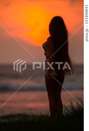 Silhouette of woman standing on beach at sunset Silhouette of woman standing on beach at sunset 141899641