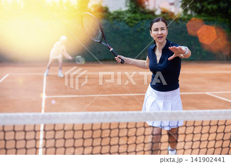 Adult woman playing doubles tennis on court 141902441