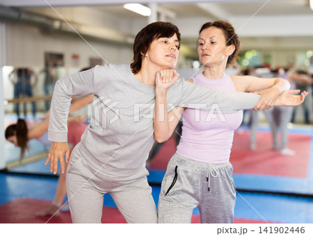 Women in pair perform effective impact on pain points while learning self-defense. 141902446
