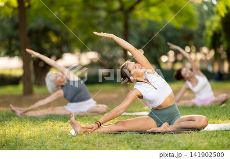 Young woman doing stretching in park Young woman doing stretching in park 141902500