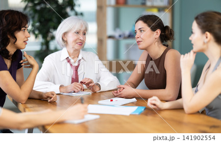 Group of women solving problems sitting around the table Group of women solving problems sitting around the table 141902554