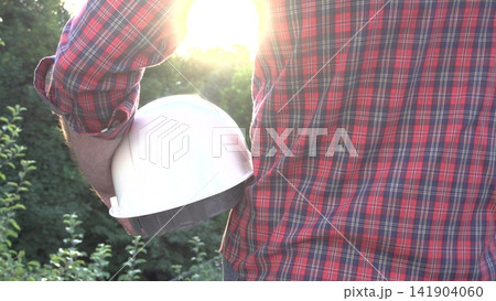 Construction worker holds a white hard hat Construction worker holds a white hard hat 141904060