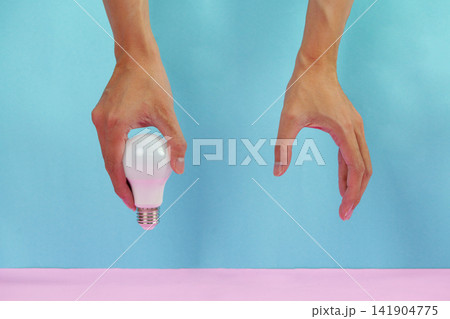 Cropped hands holding LED light bulb on blue and pink background for idea concept Cropped hands holding LED light bulb on blue and pink background for idea concept 141904775