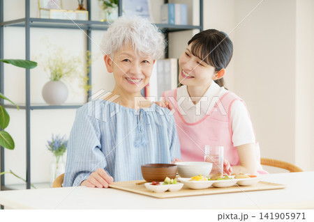 食事を前に微笑む日本人シニア女性と若い日本人看護師 食事を前に微笑む日本人シニア女性と若い日本人看護師 141905971