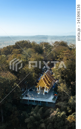 Wat Phra That Chom Kitti surrounded by dense green forest, overlooking the peaceful Chiang Rai countryside beneath a clear blue sky on 13 January 2023. 141906136