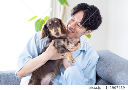 ファミリー 犬のいる暮らし ソファーでくつろぐ男性と犬 ファミリー 犬のいる暮らし ソファーでくつろぐ男性と犬 141907489