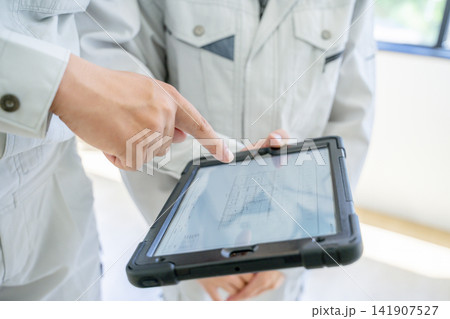 タブレットを見ながら打ち合わせをする作業員 タブレットを見ながら打ち合わせをする作業員 141907527